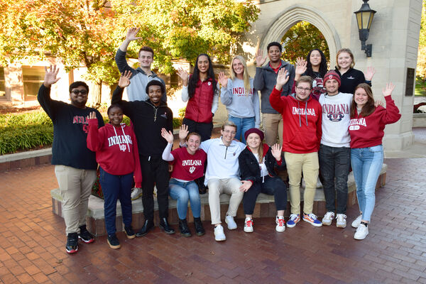 Smiling IU students wave at the camera, in front of the Sample Gates image number null